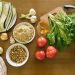 Top view of fresh vegetables and ingredients on a wooden table, ideal for healthy recipes.